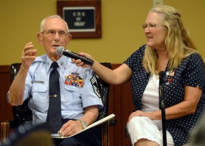 Ms. Debra Bergbower, the daughter of retired Chief Master Sgt. Harold Bergbower, 26th Calvary Regiment air mechanic, holds the microphone for him during his guest speaking for Focus 56 at Luke Air Force Base, Ariz., May 15, 2014. Bergbower is a POW and was help in captivity from May 1943 until August 18945. (U.S. Air Force photo by Senior Airman Devante Williams)